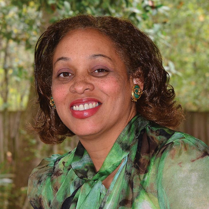 a smiling woman with a green leafy background