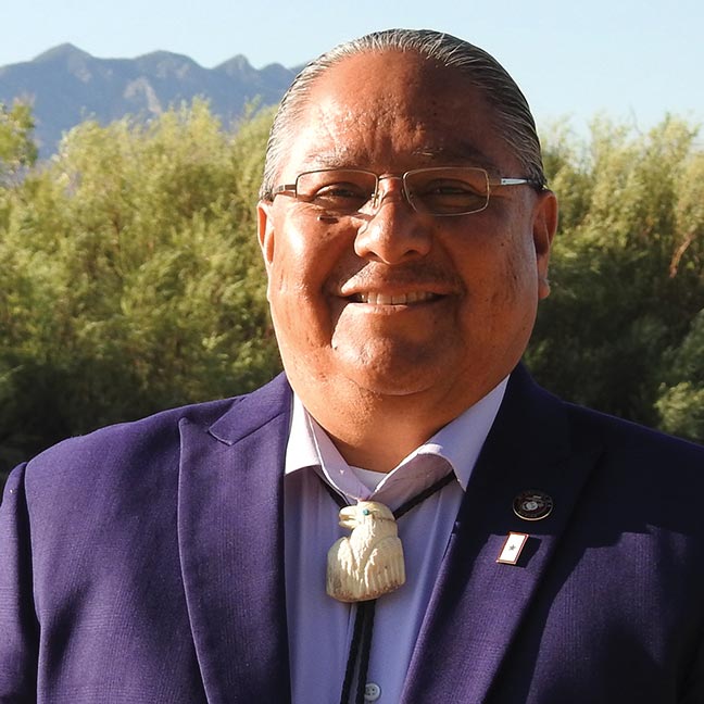 a smiling man wearing a bolo tie with the head of an eagle